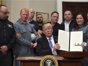 President Donald Trump holds up a proclamation on steel imports during an event at the White House in Washington, Thursday, March 8, 2018. He also signed one for aluminum.
