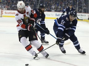 Erik Karlsson battles the Winnipeg Jets' Mark Scheifele during December 2017.