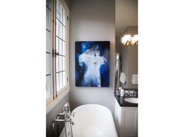 The master bath offers a spa experience with clawfoot soaker tub, walk-in shower, double sink vanity and classic black-and-white basket weave tiles. The Virginie Bocaert artwork is from Koyman Galleries.