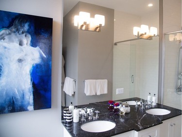 The master bath offers a spa experience with clawfoot soaker tub, walk-in shower, double sink vanity and classic black-and-white basket weave tiles. The Virginie Bocaert artwork is from Koyman Galleries.