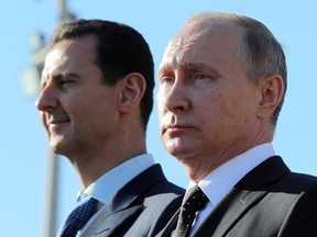 This Dec. 11, 2017 file photo, shows Russian President Vladimir Putin, right, and Syrian President Bashar Assad watching troops march at the Hemeimeem air base in Syria.