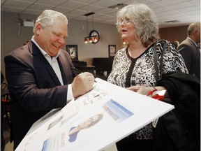 Ontario Progressive Conservative party leader Doug Ford signs an anti-Liberal sign made by Janine LeClerc of Trenton Wednesday.