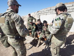 Canadian special forces soldiers, left and right, speak with Peshmerga fighters at an observation post, Monday, February 20, 2017 in northern Iraq.