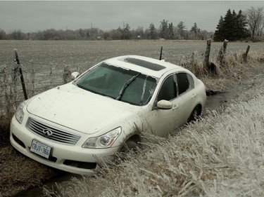 A car lies in the ditch on a country road off Leitrim Road Monday while the road shoulders were pure ice.  Freezing rain across the city knocked out power lines, snarled traffic and generally wreaked havoc across the capital Monday (April 16, 2018).