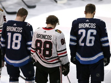 Bryan Little #18 and Blake Wheeler #26 of the Winnipeg Jets and Patrick Kane #88 of the Chicago Blackhawks honour those involved in the Humboldt Broncos bus crash tragedy before NHL action on April 7, 2018 at Bell MTS Place in Winnipeg.