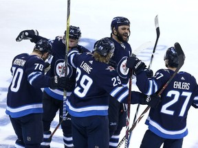 Joe Morrow #70, Paul Stastny #25, Patrik Laine #29, Dustin Byfuglien #33 and Nikolaj Ehlers #27 of the Winnipeg Jets celebrate Morrow's game-winning goal against the Minnesota Wild in Game One of the Western Conference First Round during the 2018 NHL Stanley Cup Playoffs on April 11, 2018 at Bell MTS Place in Winnipeg, Manitoba, Canada.