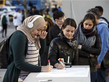 TORONTO, ON - APRIL 23: A woman wipes away tears as she signs a memorial card for the victims near the scene on Yonge St. at Finch Ave., after a van plowed into pedestrians on April 23, 2018 in Toronto, Canada. A suspect identified as Alek Minassian, 25, is in custody after a driver in a white rental van collided with multiple pedestrians killing nine and injuring at least 16.