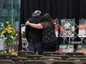 A man is comforted as he looks at photographs prior to a vigil at the Elgar Petersen Arena, home of the Humboldt Broncos, to honour the victims of a fatal bus accident in Humboldt, Canada, April 8, 2018. Mourners in the tiny Canadian town of Humboldt, still struggling to make sense of a devastating tragedy, prepared Sunday for a prayer vigil to honor the victims of the truck-bus crash that killed 15 of their own and shook North American ice hockey.