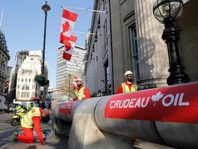 Demonstrators use a mock oil pipeline to block the entrance to the Canadian High Commission in central London on April 18, 2018, as they protest the Trans Mountain oil pipeline from Alberta's oil sands to the Pacific Ocean.