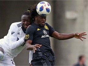 Columbus Crew defender Lalas Abubakar, right, hits a header alongside Vancouver Whitecaps defender Doneil Henry (2) in the second half of an MLS soccer game in Columbus, Ohio, Saturday, March 31, 2018.