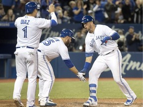Toronto Blue Jays' Justin Smoak, right, is greeted at home plate by teammates Aledmys Diaz and Russell Martin after he hit a grand slam against the New York Yankees in the eighth inning of their American League MLB baseball game in Toronto on Sunday April 1, 2018.