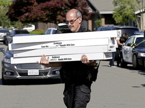 John Lopes, a crime scene investigator for the Sacramento County Sheriff's office, carries boxes of evidence taken from the home of murder suspect Joseph DeAngelo to a sheriff's vehicle Thursday, April 26, 2018, in Citrus Heights, Calif. DeAngelo, 72, was taken into custody Tuesday on suspicion of committing multiple homicides and rapes in the 1970s and 1980s in California. Authorities spent the day going through the home for evidence.