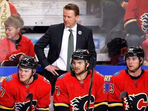 In this Saturday, April 7, 2018, file photo, Calgary Flames coach Glen Gulutzan, top, watches during the team's NHL hockey game against the Vegas Golden Knights in Calgary, Alberta. The Flames fired Gulutzan on Tuesday, April 17, 2018, after two years with the club. Assistant coaches Dave Cameron and Paul Jerrard were also relieved of their duties.