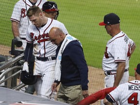Atlanta Braves' Freddie Freeman leaves the field with a trainer as manager Brian Snitker watches after Freeman was hit by a pitch by Philadelphia Phillies' Hoby Milner during the eighth inning of a baseball game Wednesday, April 18, 2018, in Atlanta.
