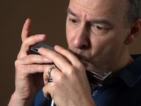 Normand Glaude playing the harmonica while rehearsing for an upcoming performance.