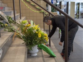 Steve Hogle, president of the Saskatoon Blades of the Western Hockey League, places flowers at a memorial at Elgar Petersen Arena in Humboldt on Saturday.