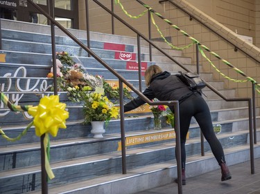 A woman lays flowers at a memorial on the stairs leading into Elgar Petersen Arena, home of the Humboldt Broncos hockey team.