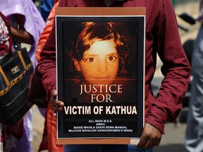 An Indian woman holds a poster with a portrait of Asifa, an 8 year-old girl who was grazing her family's ponies in the forests of the Himalayan foothills when she was kidnapped and her mutilated body found in the woods a week later, in Srinagar, Indian controlled Kashmir.