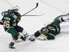 Minnesota Wild goalie Devan Dubnyk, right, makes a diving stop on a shot by Winnipeg Jets' Patrik Laine as Wild's Jared Spurgeon, left, defends against Laine during the third period of Game 4 of an NHL hockey first-round playoff series Tuesday, April 17, 2018, in St. Paul, Minn. The Jets won 2-0.