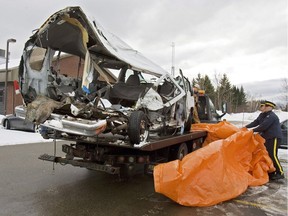 In this file picture, RCMP officers remove the tarp covering a van that was carrying the Bathurst High School boys' basketball team. It collided with a transport truck while returning from a game in Bathurst, N.B., 10 years ago, on Jan. 12, 2008.