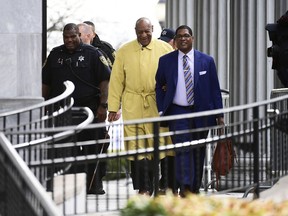 Bill Cosby, center, leaves his sexual assault trial lead by spokesperson Andrew Wyatt, right, at the Montgomery County Courthouse, Monday, April 2, 2018, in Norristown, Pa.