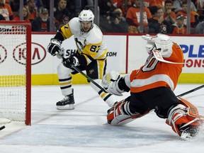 Pittsburgh Penguins' Sidney Crosby, left, scores past Philadelphia Flyers' Michal Neuvirth during the first period in Game 6 of an NHL first-round hockey playoff series Sunday, April 22, 2018, in Philadelphia.
