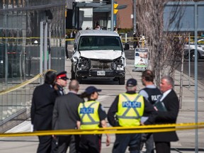 Police are seen near a damaged van in Toronto after a van mounted a sidewalk crashing into a number of pedestrians on Monday, April 23, 2018.
