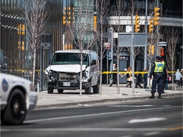 Police are seen near a damaged van in Toronto after a van mounted a sidewalk crashing into a number of pedestrians on Monday, April 23, 2018.