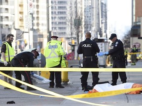 Police secure an area around a covered body in Toronto after a van mounted a sidewalk crashing into a number of pedestrians on Monday, April 23, 2018.