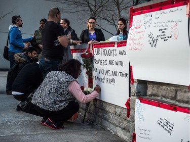 People deliver flowers and write their condolences on a memorial to the victims after a van hit a number of pedestrians on Yonge Street and Finch in Toronto on Monday, April 23, 2018. Ten people died and 15 others were injured when a van mounted a sidewalk and struck multiple pedestrians along a stretch of one of Toronto's busiest streets.