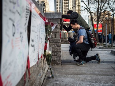 People deliver flowers and write their condolences on a memorial to the victims after a van hit a number of pedestrians on Yonge Street and Finch in Toronto on Monday, April 23, 2018. Ten people died and 15 others were injured when a van mounted a sidewalk and struck multiple pedestrians along a stretch of one of Toronto's busiest streets.