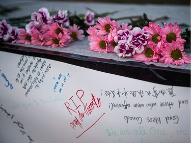 People deliver flowers and write their condolences on a memorial to the victims after a van hit a number of pedestrians on Yonge Street and Finch in Toronto on Monday, April 23, 2018. Ten people died and 15 others were injured when a van mounted a sidewalk and struck multiple pedestrians along a stretch of one of Toronto's busiest streets.