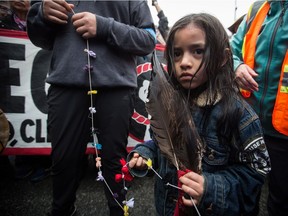 A young girl holds an eagle feather as protesters opposed to the Kinder Morgan Trans Mountain pipeline extension defy a court order and block an entrance to the company's property, in Burnaby, B.C., on Saturday April 7, 2018. The pipeline is set to increase the capacity of oil products flowing from Alberta to the B.C. coast to 890,000 barrels from 300,000 barrels.