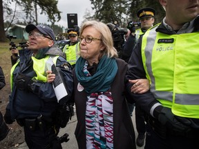 Federal Green Party Leader Elizabeth May, centre, is arrested by RCMP officers after joining protesters outside Kinder Morgan's facility in Burnaby, B.C., on Friday March 23, 2018.