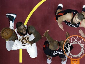 Cleveland Cavaliers' LeBron James shoots as Toronto Raptors' OG Anunoby and Jonas Valanciunas, right, defend during the first half of an NBA basketball game Tuesday, April 3, 2018, in Cleveland.