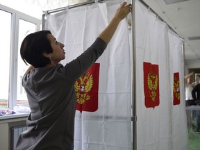 A polling station official prepares vote cabins for the 2018 Russian presidential election at a polling station in Simferopol, Crimea, March 17, 2018. Canada appears to have bowed out of the 'election observer' business abroad.