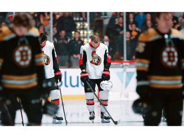 The Ottawa Senators' Mark Borowiecki, centre, bows his head between the Boston Bruins' Charlie McAvoy, foreground left, and Noel Acciari, right, during a moment of silence for the Humboldt Broncos bus crash victims before an NHL hockey game in Boston, Saturday, April 7, 2018.