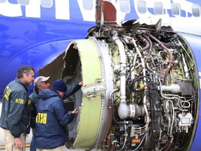 National Transportation Safety Board investigators examine damage to the engine of the Southwest Airlines plane that made an emergency landing at Philadelphia International Airport in Philadelphia on Tuesday, April 17, 2018. The Southwest Airlines jet blew the engine at 32,000 feet and got hit by shrapnel that smashed a window, setting off a desperate scramble by passengers to save a woman from getting sucked out. She later died, and seven others were injured.