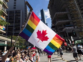 A man holds a flag on a hockey stick during the Pride parade in Toronto on June 25, 2017.