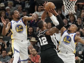 San Antonio Spurs' LaMarcus Aldridge (12) shoots against Golden State Warriors' David West (3) and Kevin Durant during the first half of Game 4 of a first-round NBA basketball playoff series in San Antonio, Sunday, April 22, 2018, in San Antonio.