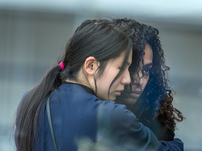 Two women embrace on Yonge Street, Tuesday April 24, next to a make shift memorial put in place in remembrance of those killed and injured in the van attack Monday.