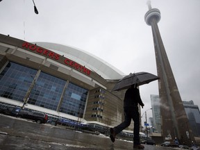 A man walks by the Rogers Centre as reports of falling ice from the CN Tower sparked a closure of parts of the area on Toronto on Monday, April 16, 2018.