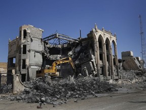 In this Thursday, April 5, 2018 photo, a bulldozer removes rubble from a government building that was destroyed last summer during fighting between U.S.-backed Syrian Democratic Forces fighters and Islamic State militants, in Raqqa, Syria. Six months after the Islamic State group was driven out, residents of Raqqa feel they have been abandoned as the world moves on. They are trying to rebuild but fear everyone around them: the Kurdish-led militia that administers the majority Arab city; Syrian government forces nearby; gangs who kidnap or rob whoever shows signs of having money; and IS militants who may still be hiding among the people.