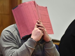 In this Feb. 26, 2015 file photo former nurse Niels Hoegel, accused of multiple murders of his patients, covers his face with a file at the district court in Oldenburg, Germany.