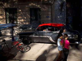 Girls walk along a street in Old Havana where a driver steers his classic American car in Havana, Cuba, Tuesday, April 17, 2018. A legislative session on Wednesday will see a historic political transition, in which President Raul Castro plans to step down and hand over the office to a younger successor.