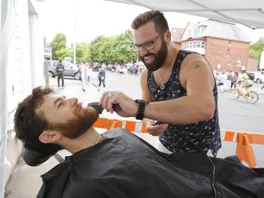 Barber Cory Trevino trims Gregory Bulte's beard in front of Hair on Second Avenue at the Great Glebe Garage Sale in Ottawa on Saturday, May 26, 2018.   (Patrick Doyle)  ORG XMIT: 0527 glebe garage sale 10