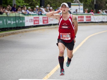 Michael Bergeron salutes as he comes in to the finish line of the marathon May 27, 2018 at Ottawa Race Weekend.    Ashley Fraser/Postmedia