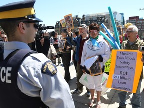 Marjorie Flowers (in white) was later on Parliament Hill while wanting to enter the Hill to place photos on the MP's desk to show the negative effects of the the Muskrat Falls megadam walk, May 7, 2018.  Labrador Inuk elders who have journeyed thousands of kilometres will be joined by supporters as they gather to rally on Parliament Hill at 11 am, following which they will attempt to nonviolently enter the House of Commons and physically place on the desks of all 343 MPs the pictures and words of those most at risk from the lethal effects of the Muskrat Falls megadam. It is part of a national day of action that will also witness demonstrations in Winnipeg, Mississauga, Goose Bay, Halifax, and St. John's.   Photo by Jean Levac/Postmedia