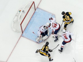 John Carlson #74 of the Washington Capitals blocks Dominik Simon #12 of the Pittsburgh Penguins as Michal Kempny #6 of the Capitals clears out the loose puck after Braden Holtby #70 of the Capitals makes a save during the third period in Game Four of the Eastern Conference Second Round during the 2018 NHL Stanley Cup Playoffs at PPG PAINTS Arena on May 3, 2018 in Pittsburgh, Pennsylvania. Pittsburgh defeated Washington 3-1.