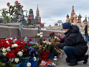 A man lays flowers in central Moscow on February 25, 2018 at the site where late opposition leader Boris Nemtsov was fatally shot on a bridge near the Kremlin.  The 55-year-old former first deputy prime minister under Boris Yeltsin was shot in the back several times just before midnight on February 27, 2015 as he walked across a bridge a stone's throw from the Kremlin walls.